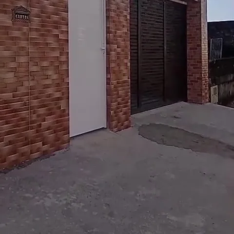 Fachada revestida em tijolinho, com porta branca e portão escuro